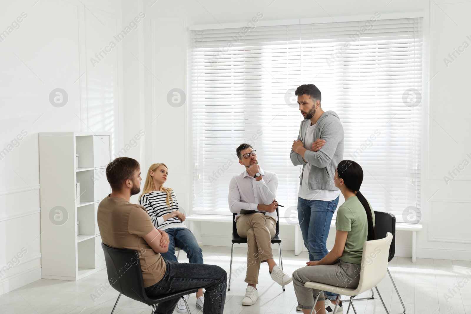 Photo of Psychotherapist working with group of drug addicted people at therapy session indoors