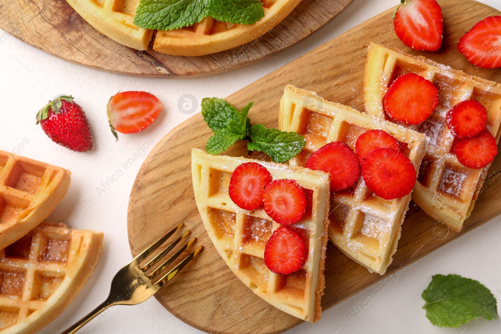 Photo of Tasty Belgian waffles with strawberries, mint and fork on white table, flat lay