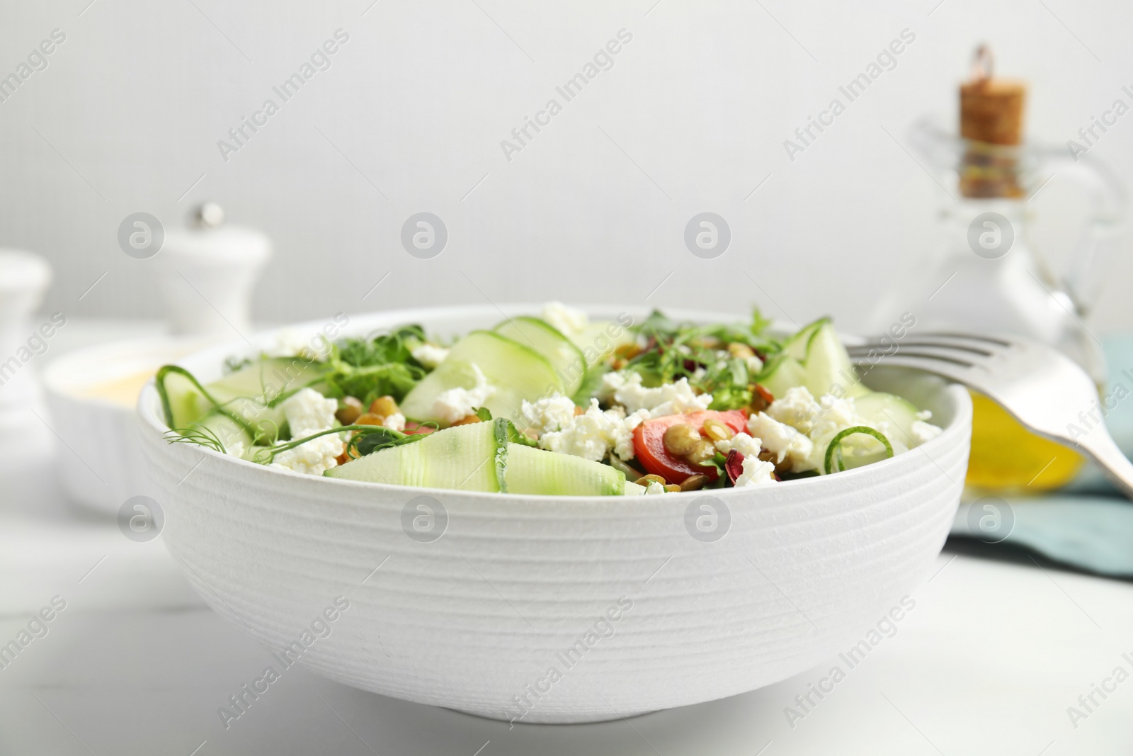 Photo of Delicious salad with lentils, vegetables and feta cheese served on white table