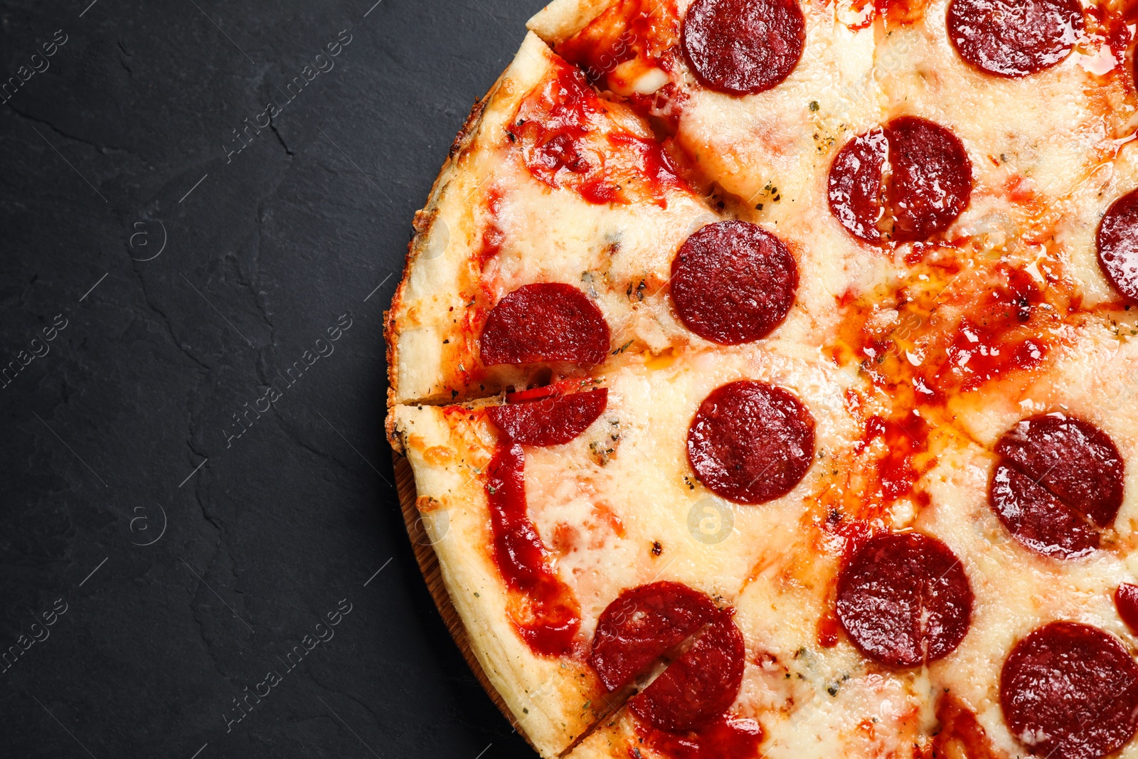 Photo of Hot delicious pepperoni pizza on dark table, top view. Space for text