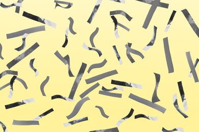 Image of Shiny silver confetti falling on light yellow background