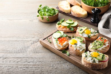 Photo of Different delicious sandwiches with microgreens on wooden table