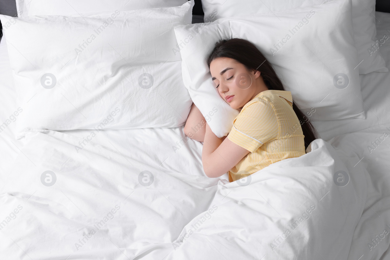 Photo of Beautiful young woman sleeping in soft bed, above view