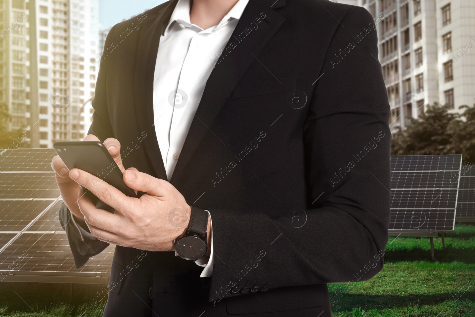 Image of Businessman with smartphone near solar panels and beautiful view of cityscape. Alternative energy source