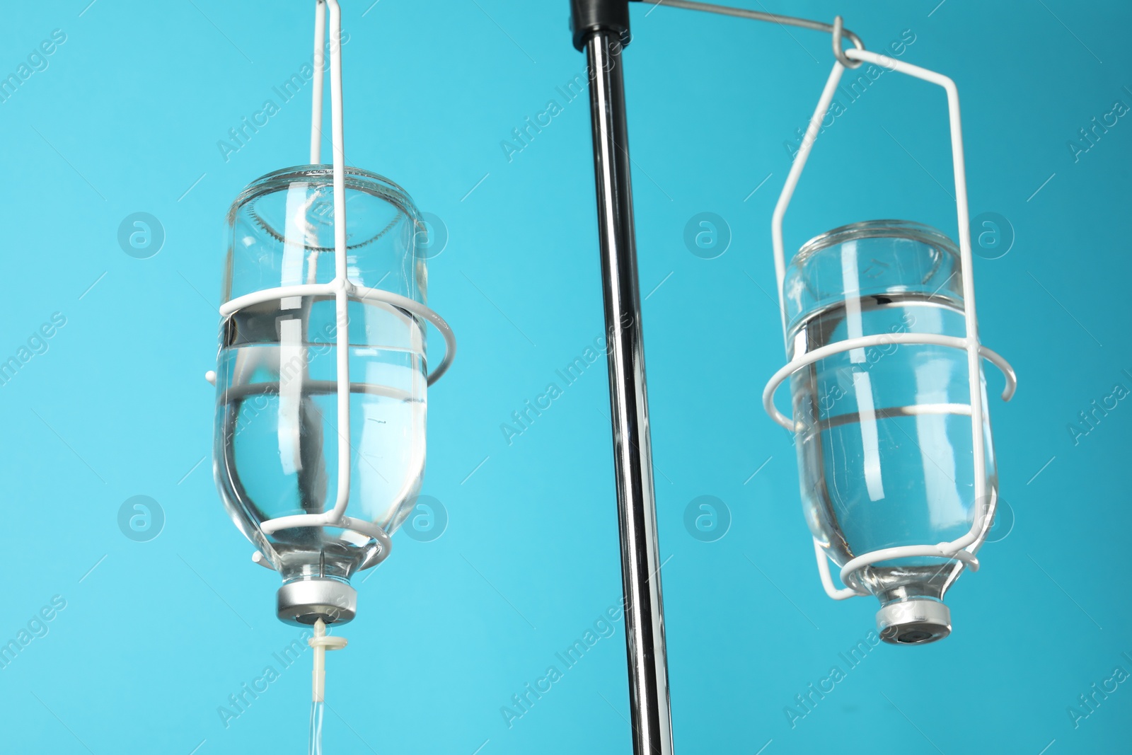 Photo of IV infusion set on pole against light blue background, closeup