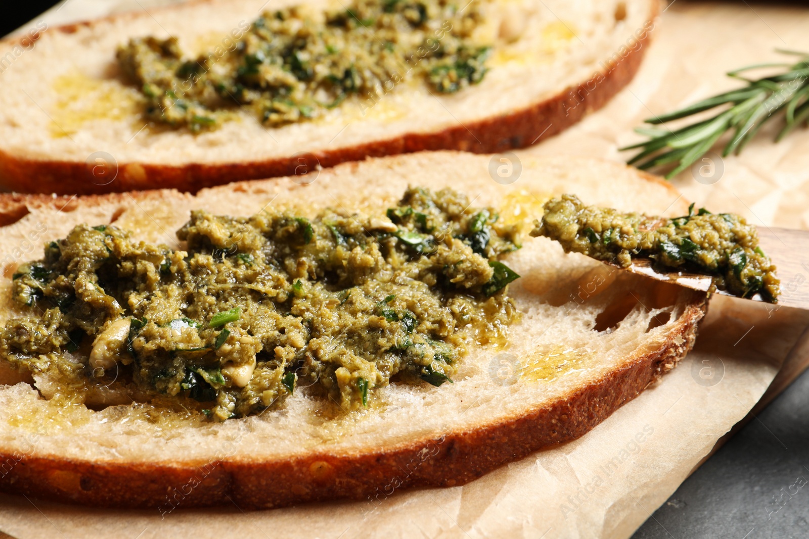 Photo of Tasty bruschettas with pesto on parchment paper, closeup