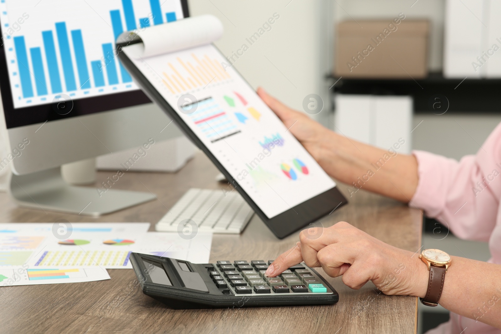 Photo of Accountant using calculator at wooden desk in office, closeup