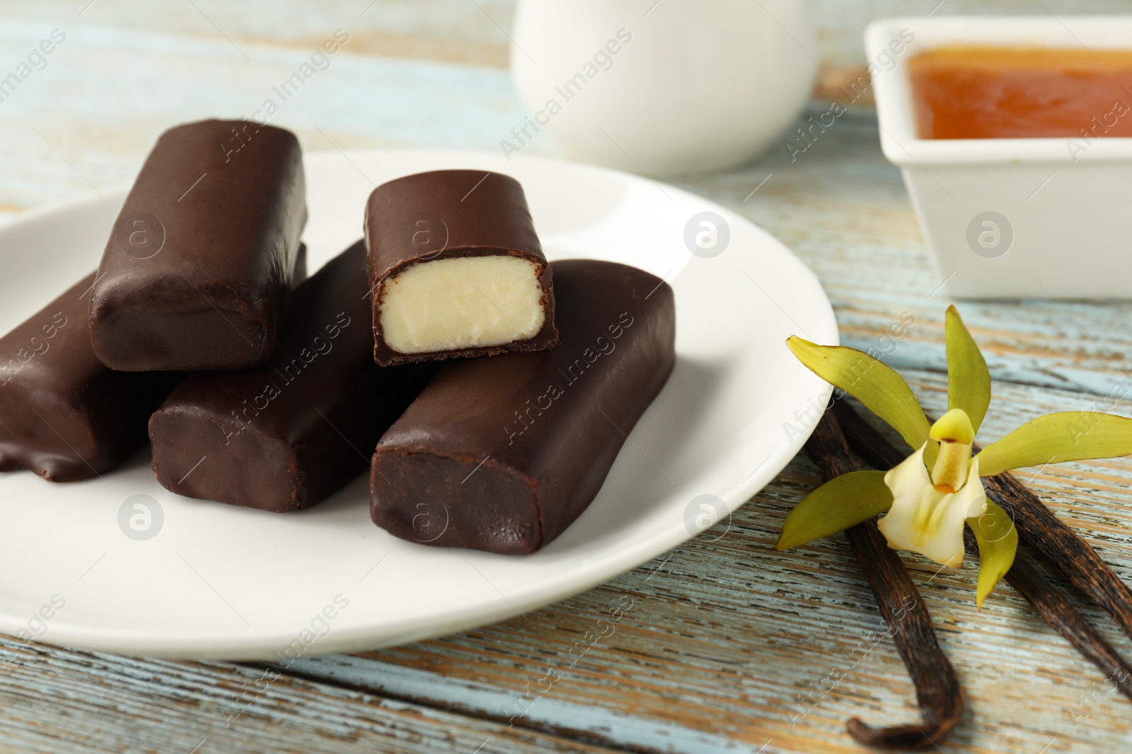 Photo of Glazed vanilla curd cheese bars served on wooden table, closeup