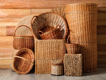 Photo of Many different wicker baskets made of natural material on floor near wooden wall