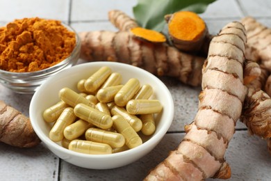 Turmeric roots, pills and powder on light tiled table, closeup