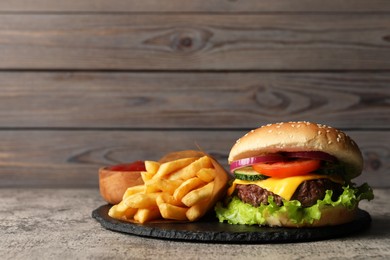 Delicious burger and french fries served on grey table. Space for text