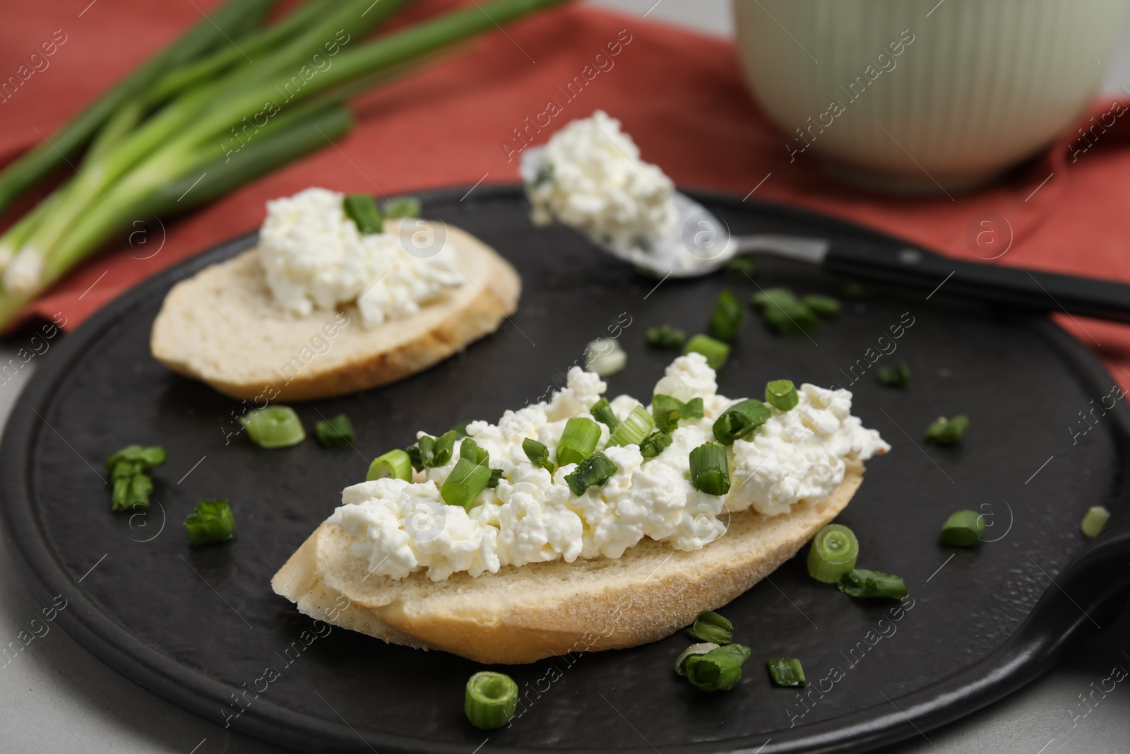 Photo of Bread with cottage cheese and green onion on grey table, closeup