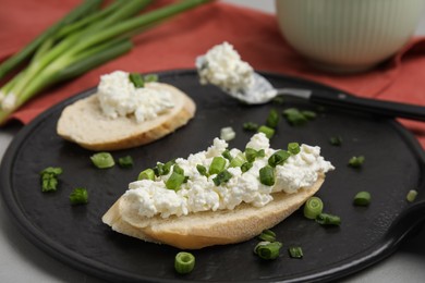 Bread with cottage cheese and green onion on grey table, closeup