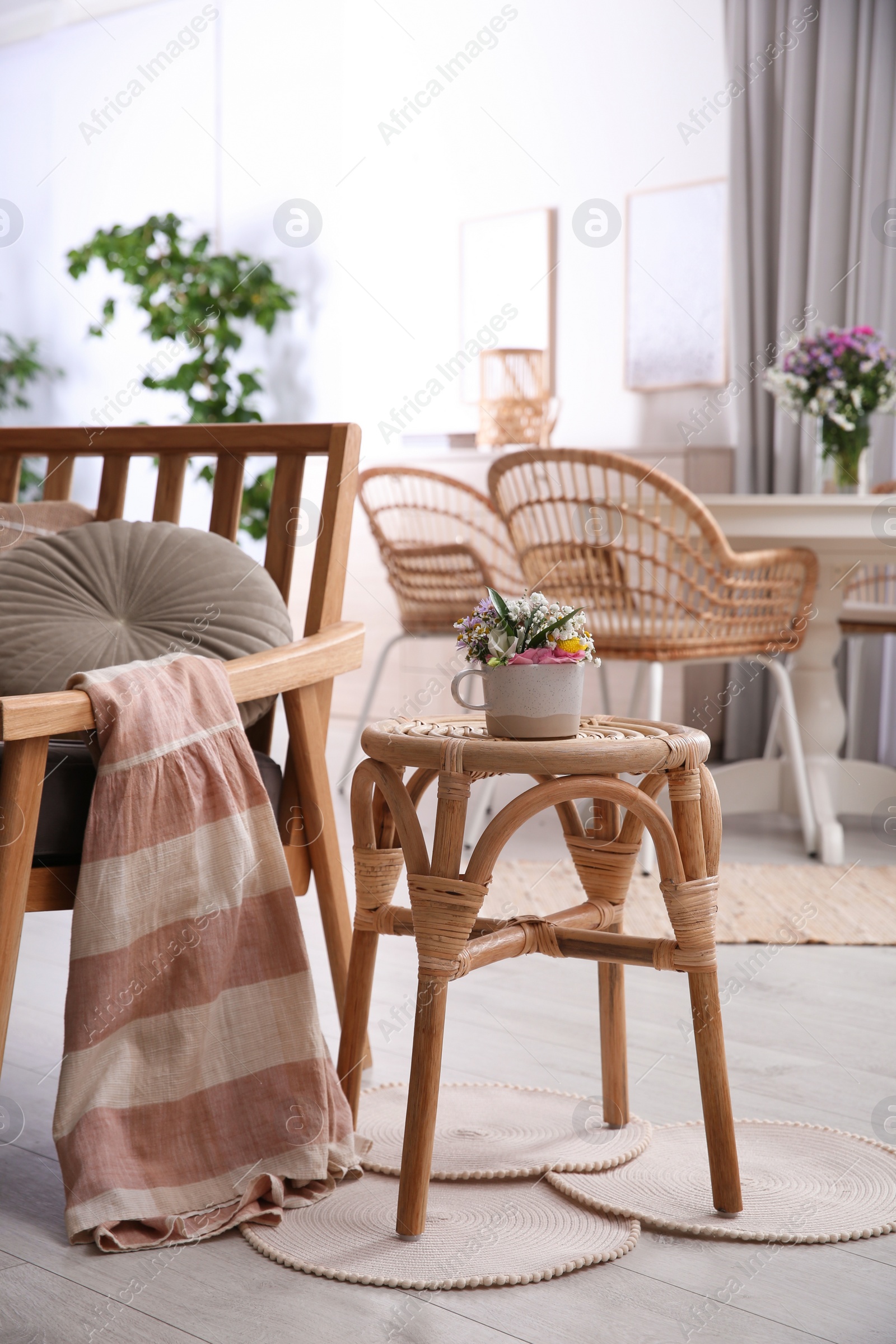 Photo of Stylish wooden stool with bouquet of flowers near armchair in room. Interior element