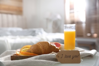 Romantic breakfast with tag saying I Love You on table in bedroom