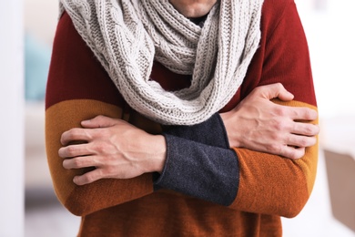 Photo of Young man in scarf suffering from cold, closeup
