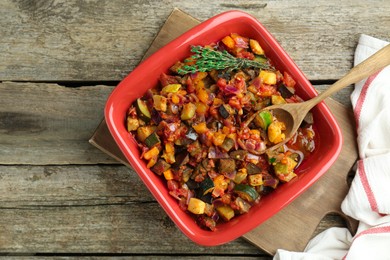 Photo of Dish with tasty ratatouille on wooden table, top view