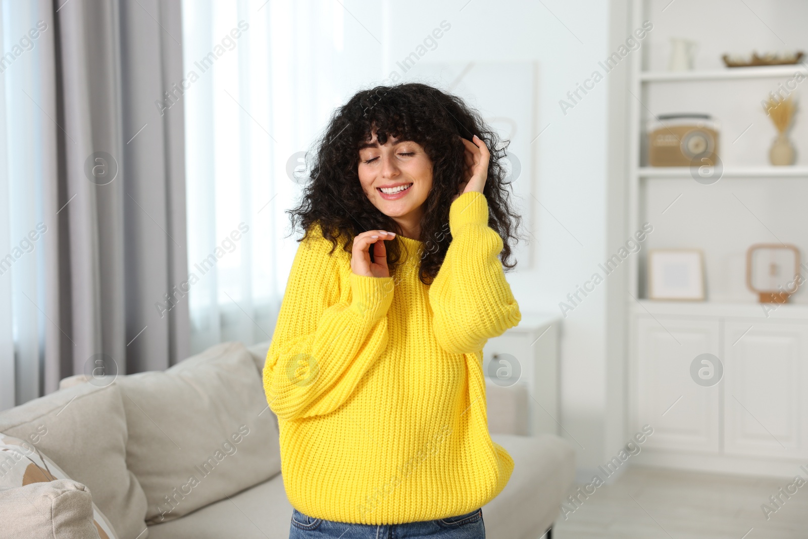 Photo of Happy young woman in stylish yellow sweater indoors