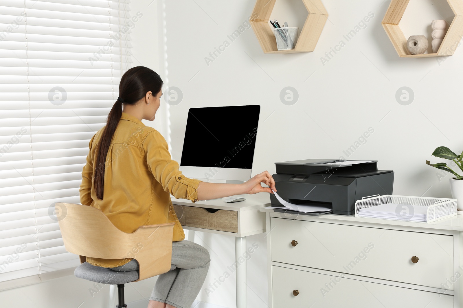 Photo of Woman using modern printer at workplace indoors