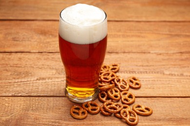 Delicious pretzel crackers and glass of beer on wooden table