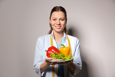 Photo of Nutritionist with healthy products on light grey background