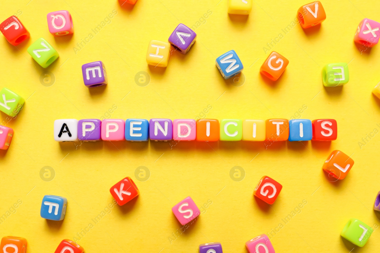 Photo of Word Appendicitis made of color cubes with letters on yellow background, flat lay