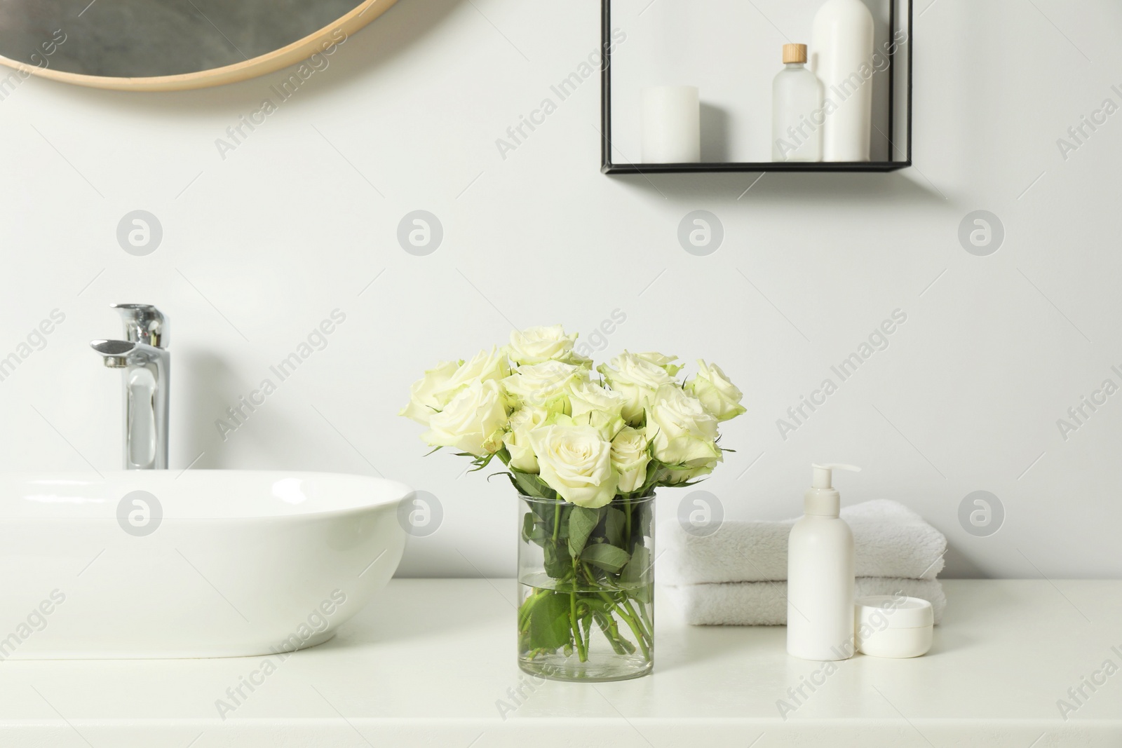 Photo of Beautiful roses and bath accessories near sink in bathroom