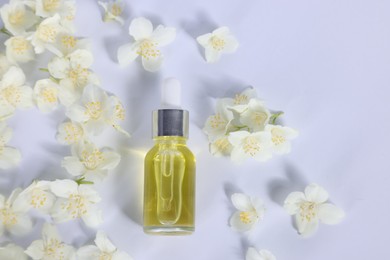 Essential oil in bottle and beautiful jasmine flowers on white background, flat lay