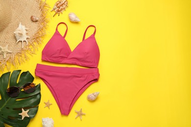 Stylish bikini and beach accessories on yellow background, flat lay. Space for text