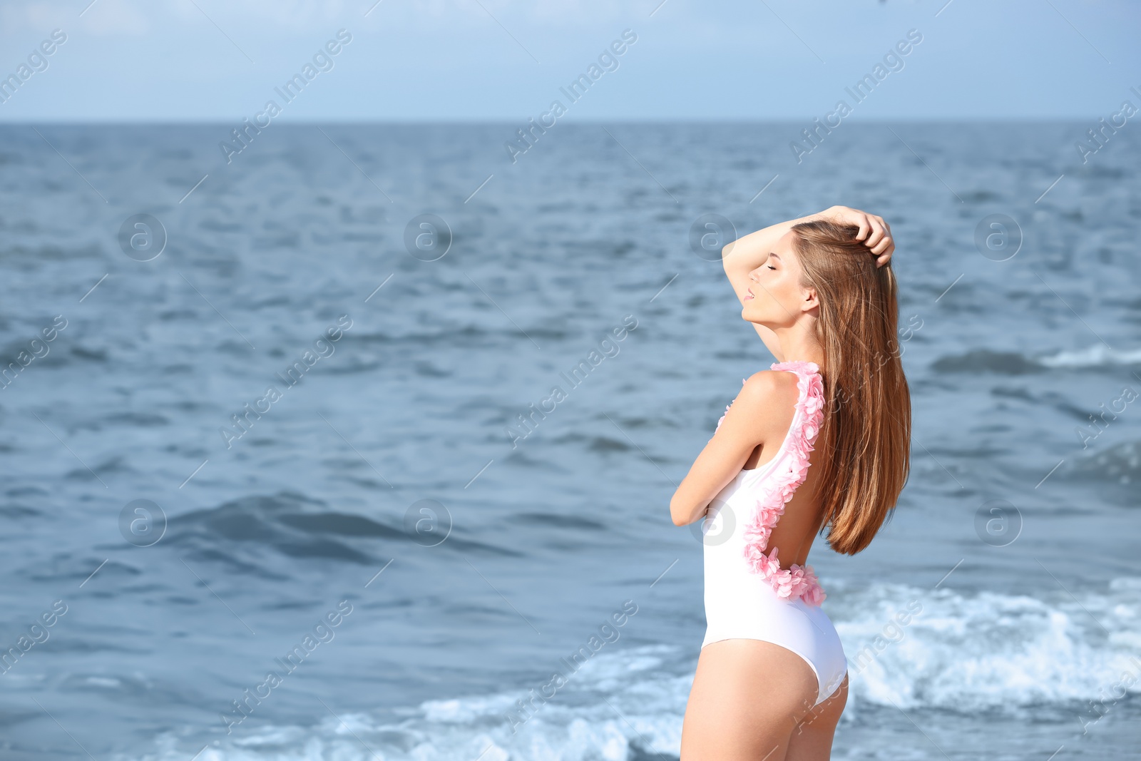 Photo of Attractive young woman in beautiful one-piece swimsuit on beach