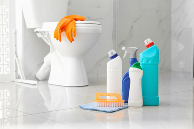 Photo of Cleaning supplies near toilet bowl in modern bathroom