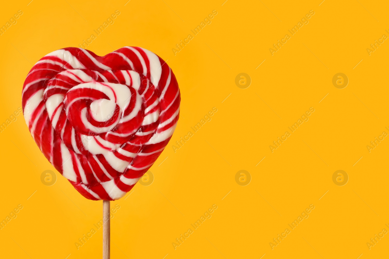 Photo of Sweet heart shaped lollipop on orange background, closeup view with space for text. Valentine's day celebration