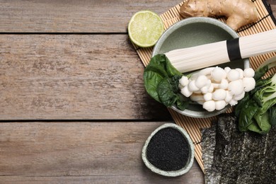 Cooking delicious ramen soup. Different ingredients on wooden table, flat lay. Space for text