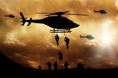 Image of Soldiers landing from helicopter on battlefield. Military service 
