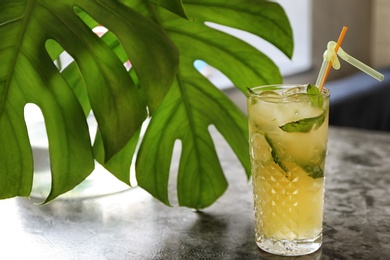 Glass of iced lemonade on table indoors