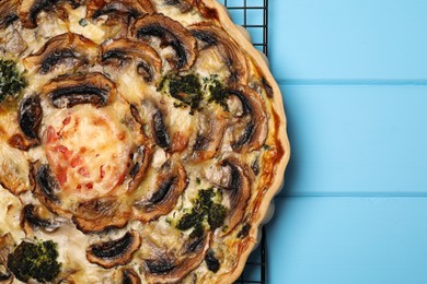 Delicious quiche with mushrooms on light blue wooden table, top view. Space for text