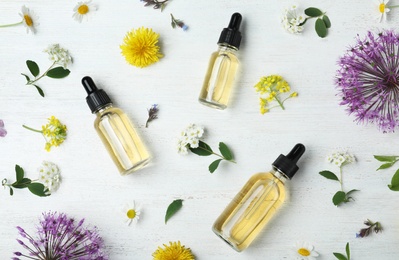Photo of Flat lay composition with essential oils and flowers on white wooden table
