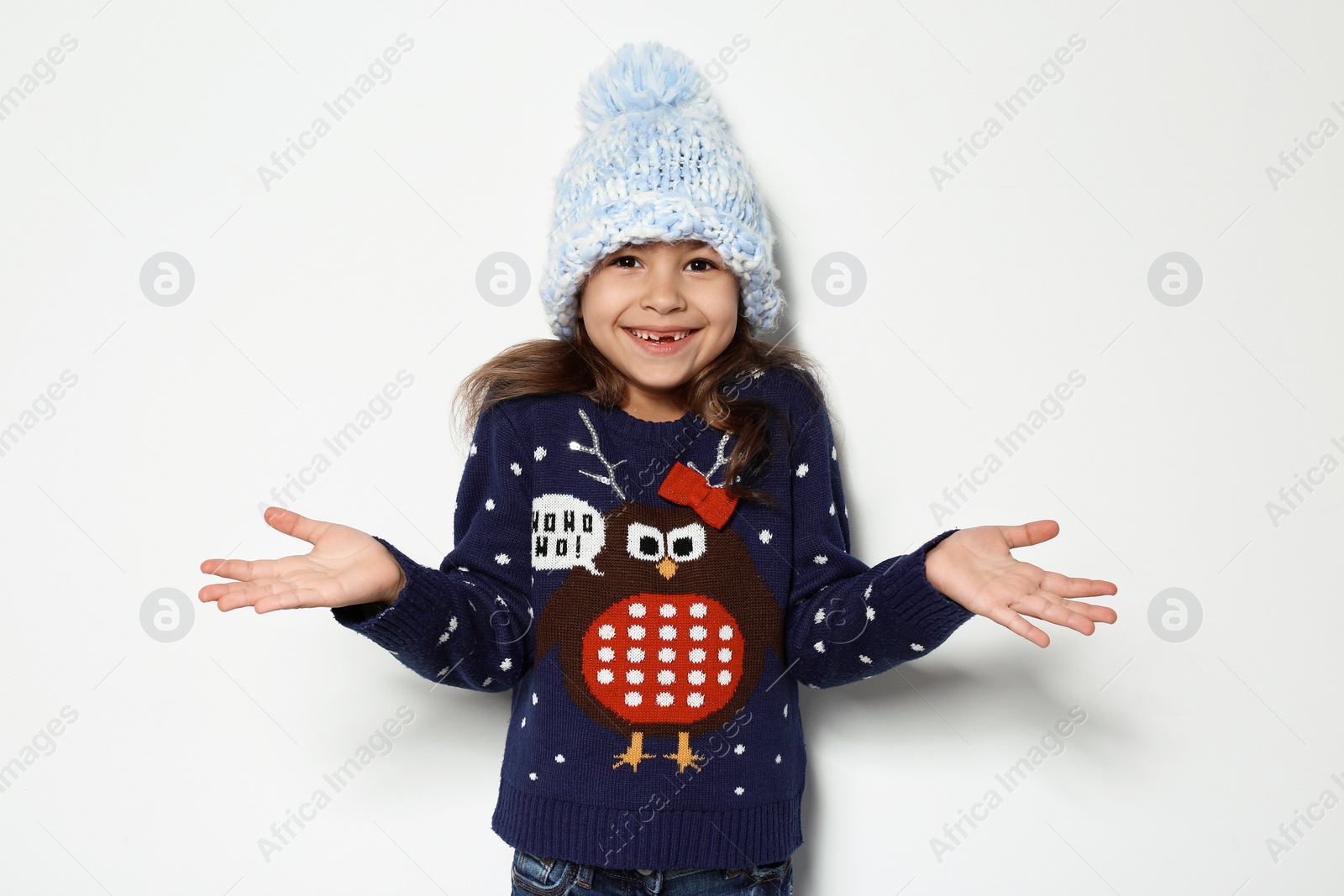 Photo of Cute little girl in Christmas sweater and knitted hat on white background