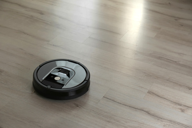 Modern robotic vacuum cleaner on wooden floor. Space for text