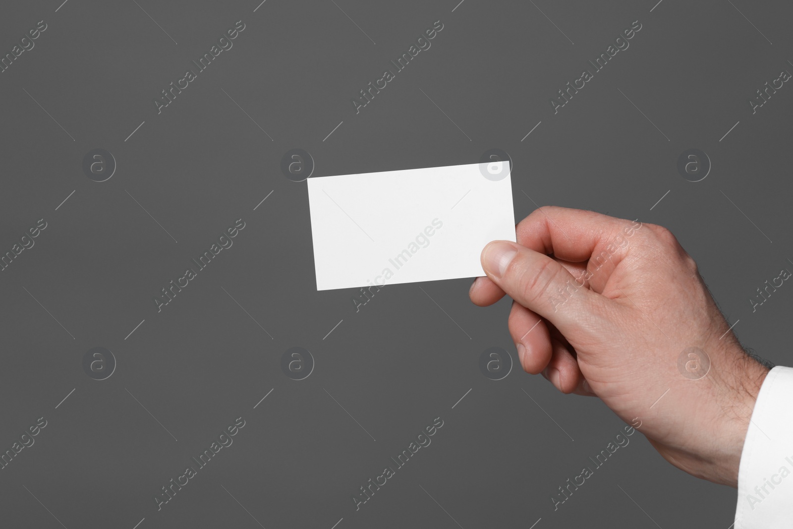 Photo of Man holding blank business card on grey background, closeup. Space for text