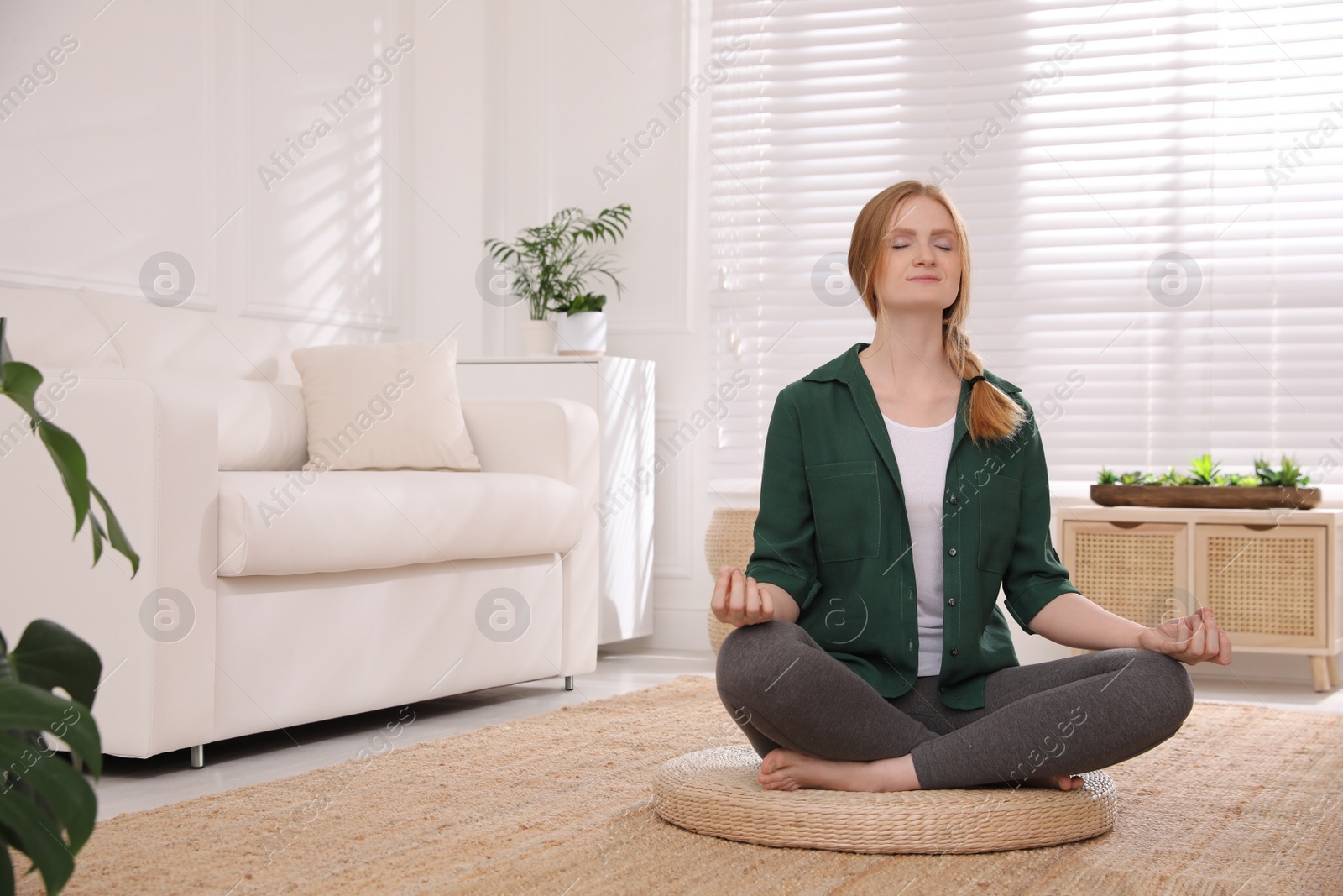 Photo of Woman meditating on wicker mat at home. Space for text