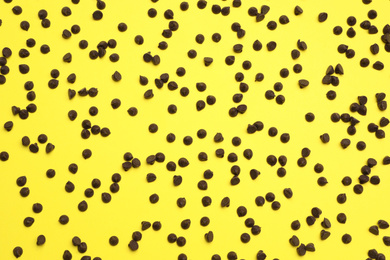 Photo of Delicious chocolate chips on yellow background, top view