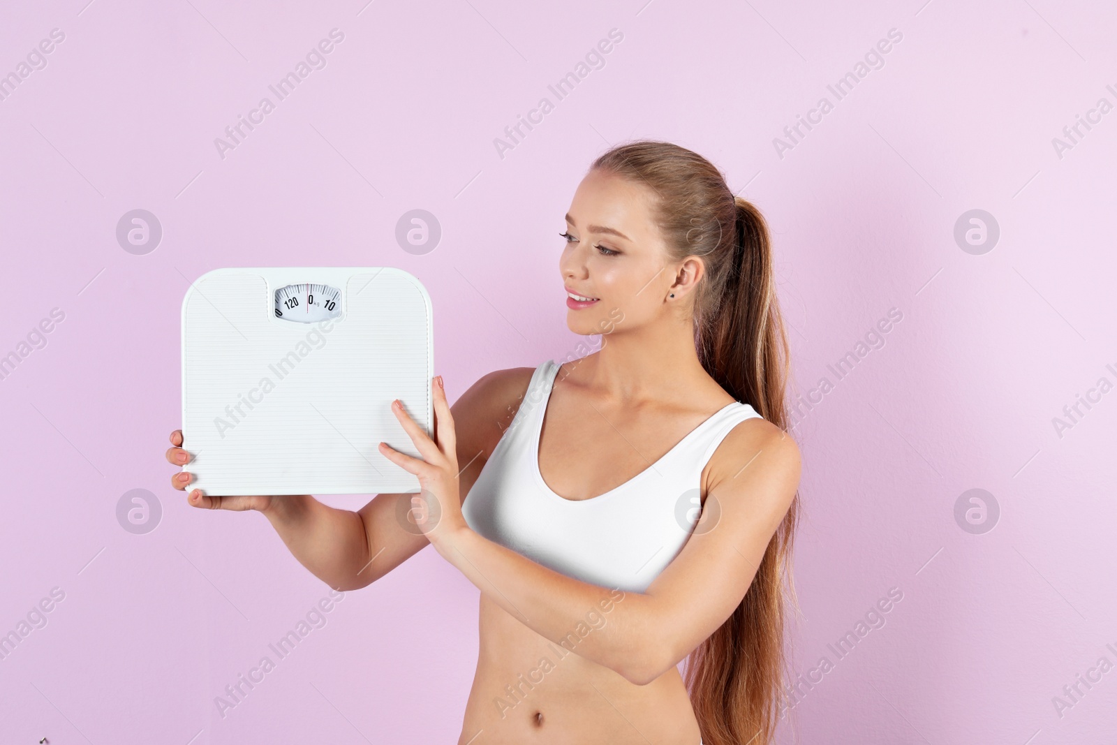 Photo of Beautiful young woman with scales on color background. Healthy diet