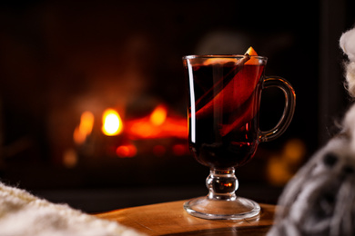 Photo of Tasty mulled wine and blurred fireplace on background