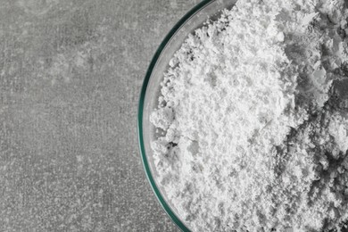 Photo of Petri dish with calcium carbonate powder on light grey table, closeup. Space for text