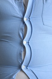 Closeup view of overweight man in tight shirt as background