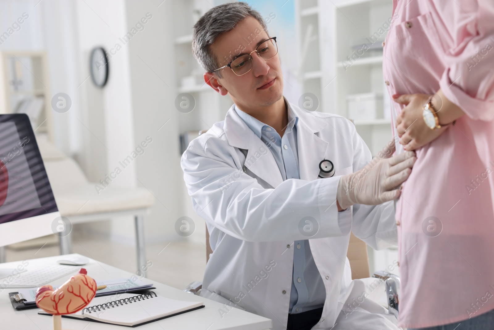 Photo of Gastroenterologist examining patient with stomach pain in clinic