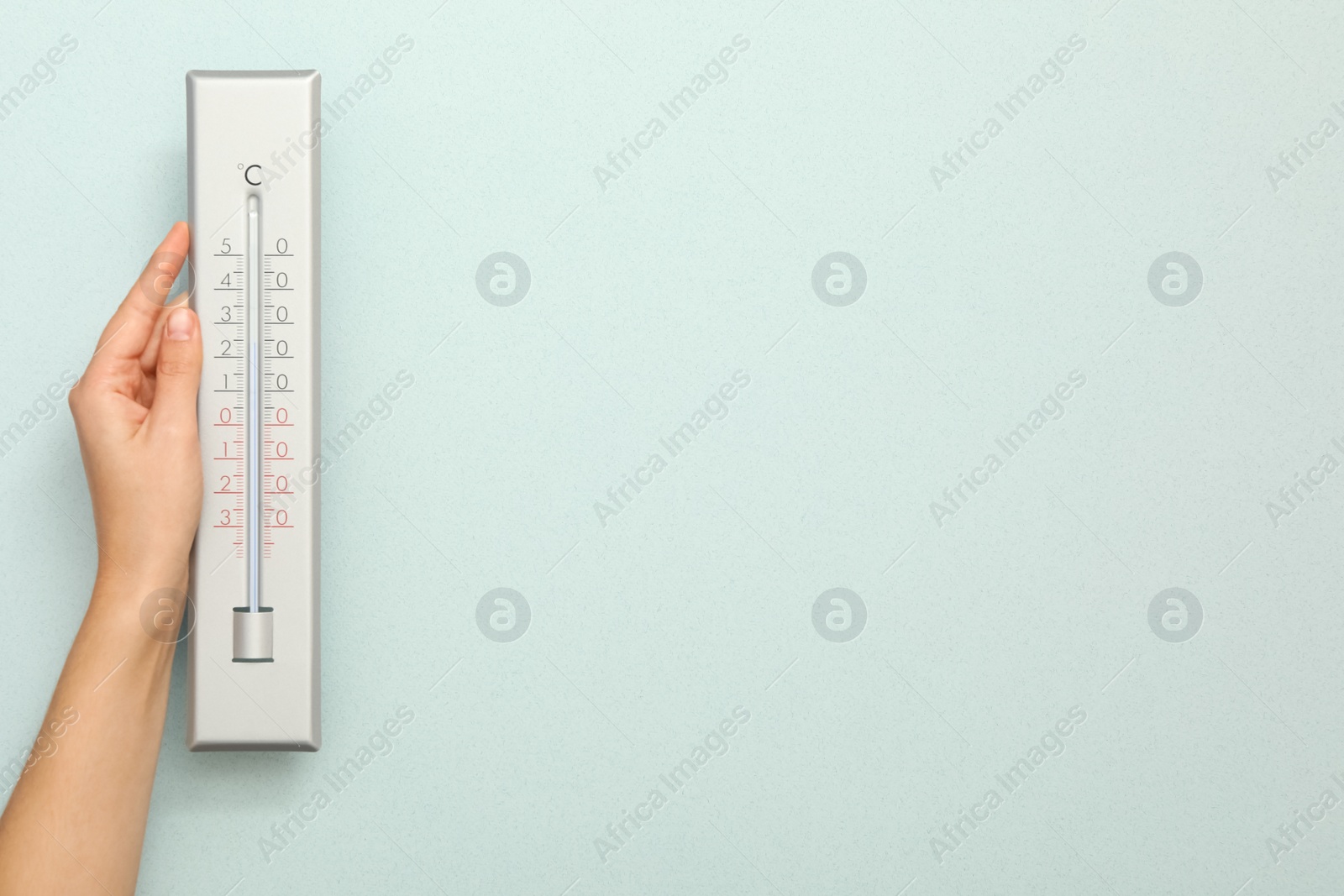 Photo of Woman with weather thermometer on light background, closeup. Space for text