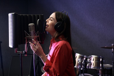 Photo of Young singer with microphone recording song in studio