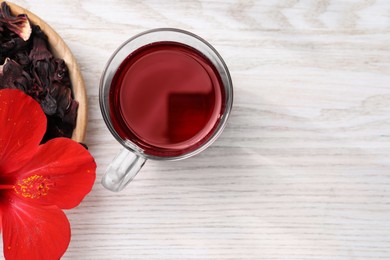 Photo of Delicious hibiscus tea and flowers on white wooden table, flat lay. Space for text